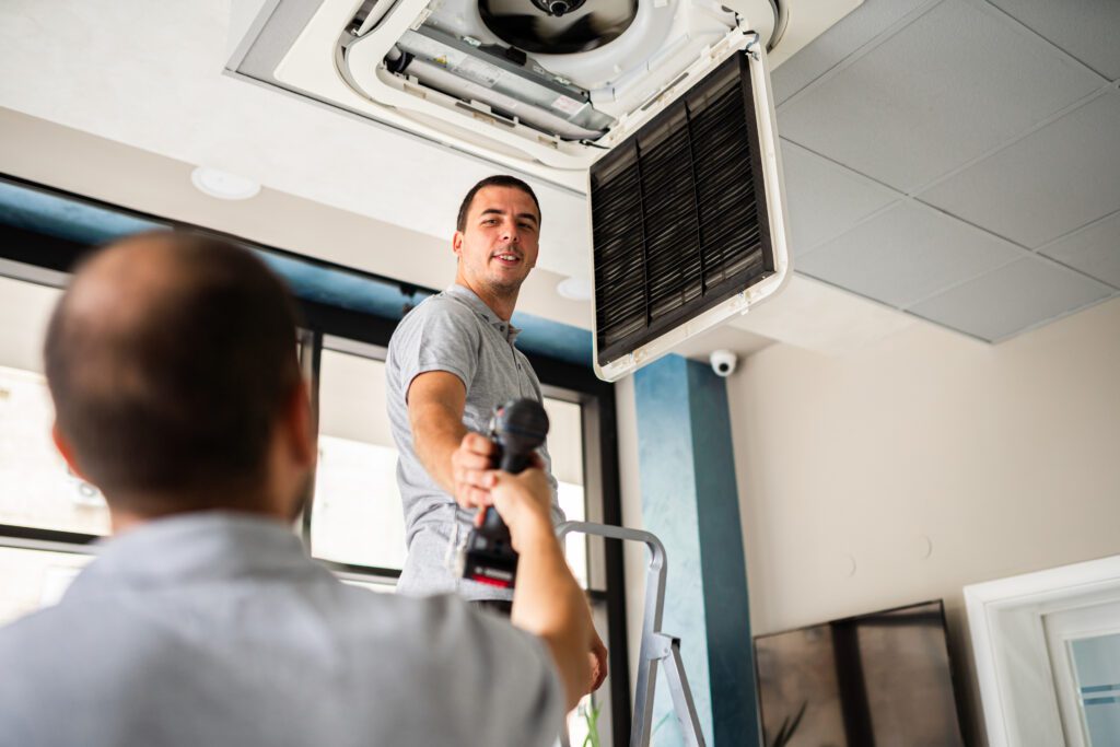 A man checks the air conditioner, Indoor Air Conditioning Maintenance with One Hour Air Conditioning & Heating of Prescott, AZ