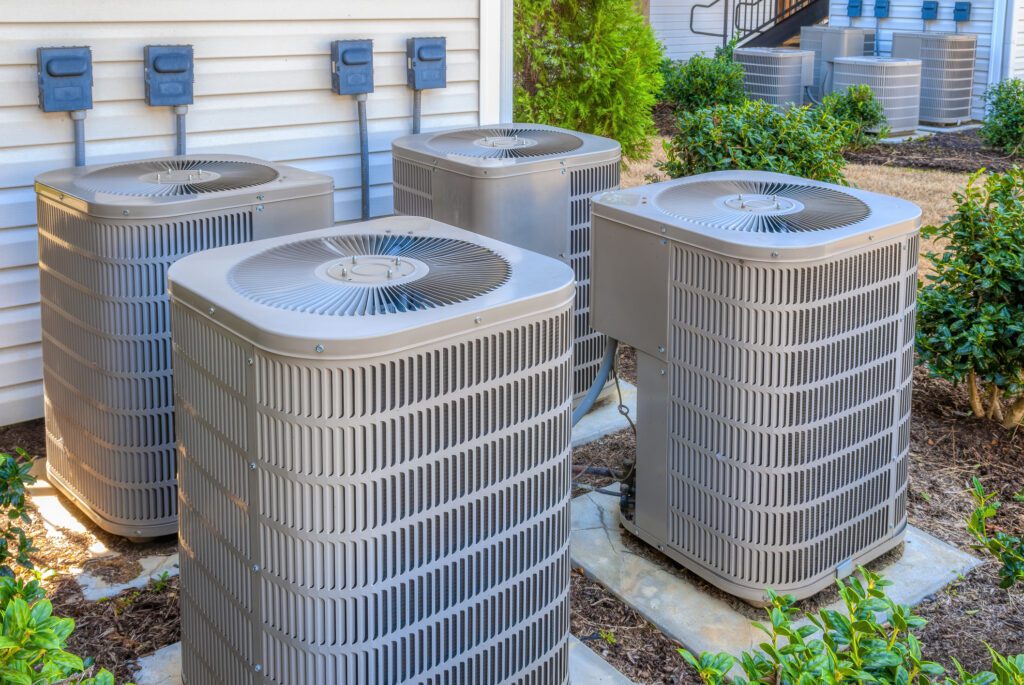 Horizontal shot of four air conditioning units outside of an upscale apartment complex.
