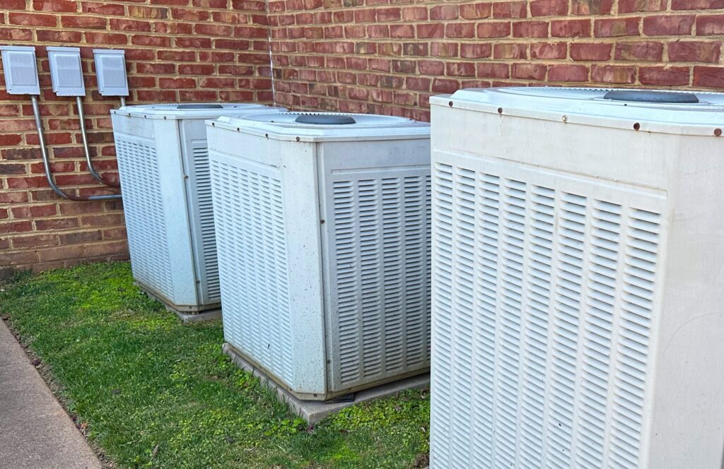 An air conditioner and heating system outdoors with green grass. Residential HVAC Systems