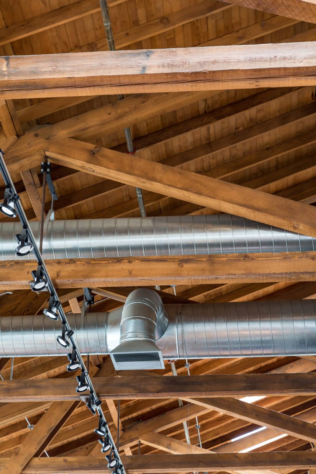 Ductwork and lights below a natural wood roof.