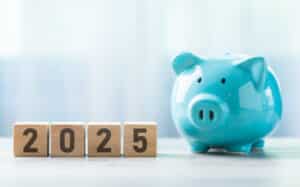 2025 is written on a wooden block beside a blue piggy bank, Smart HVAC.